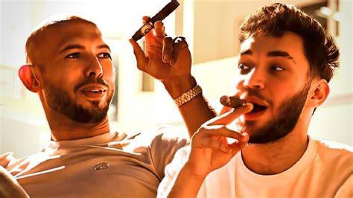 Andrew Tate smoks a cigar and poses with pizza box.